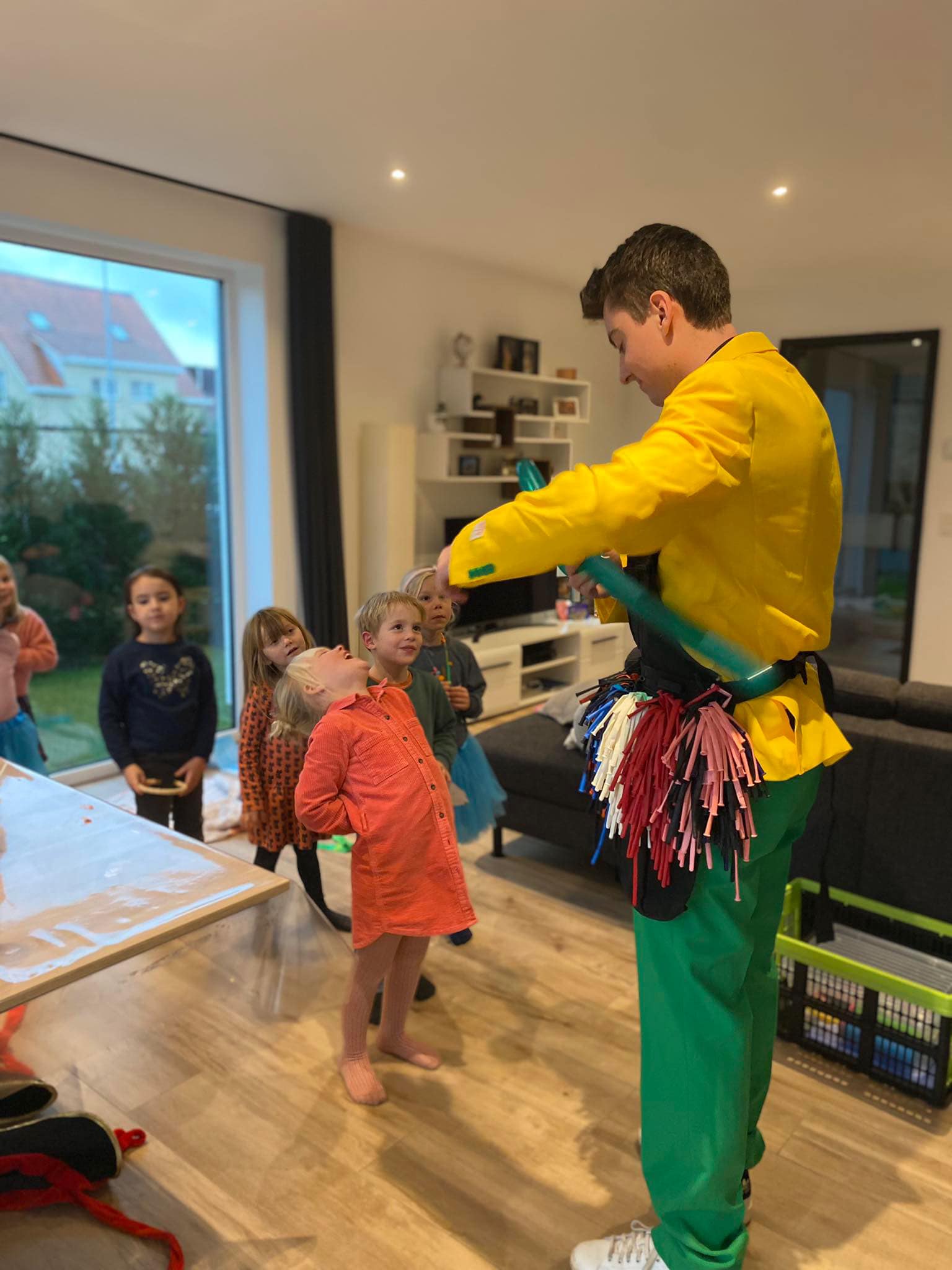 Kinderen kijken toe terwijl een ballonplooier in een geel pak een ballon plooit.