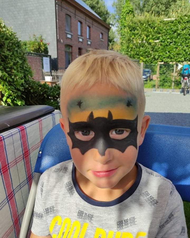 Een jongen met een zwart Batmanmasker geschminkt rond zijn ogen.