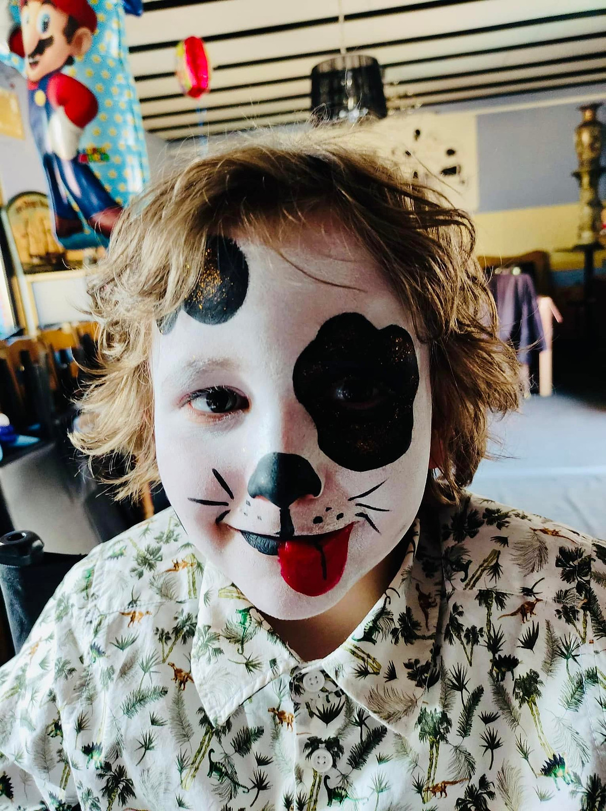 Een kind met dalmatiërgrime, met een zwarte vlek rond het oog en een rode tong.