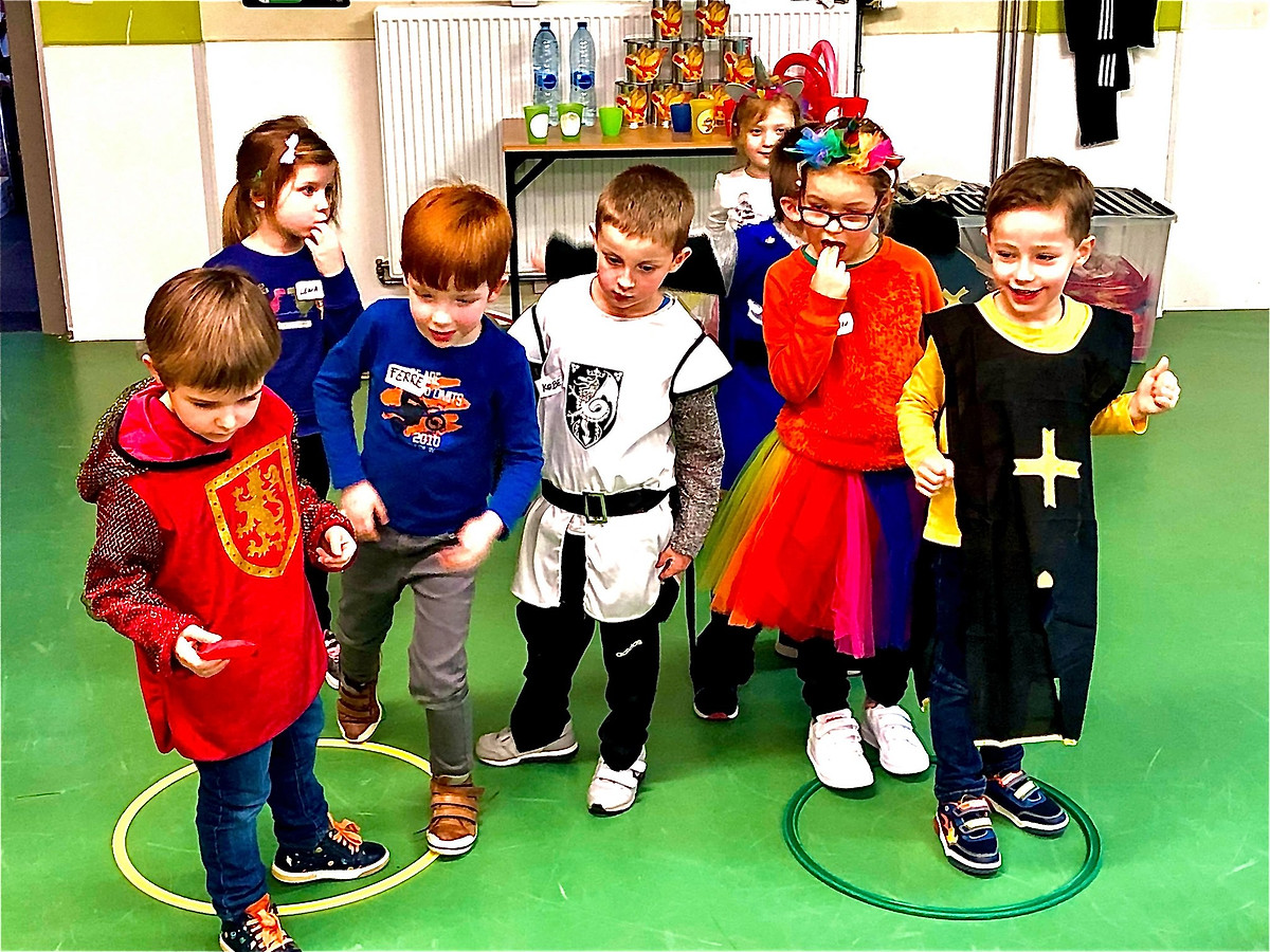 Kinderen verkleed als ridders en prinsessen spelen samen een spel in een zaal.